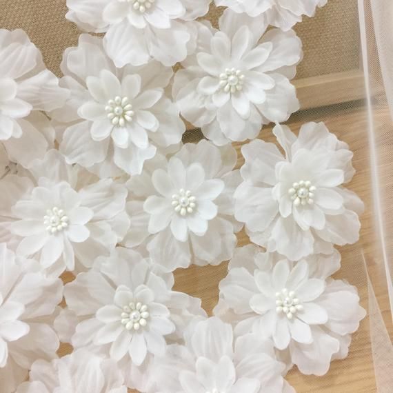 some white flowers are sitting on the floor next to a piece of cloth and sheer fabric