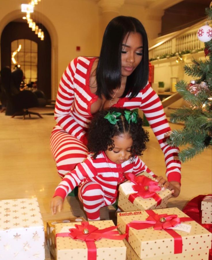 a woman and child opening presents under a christmas tree