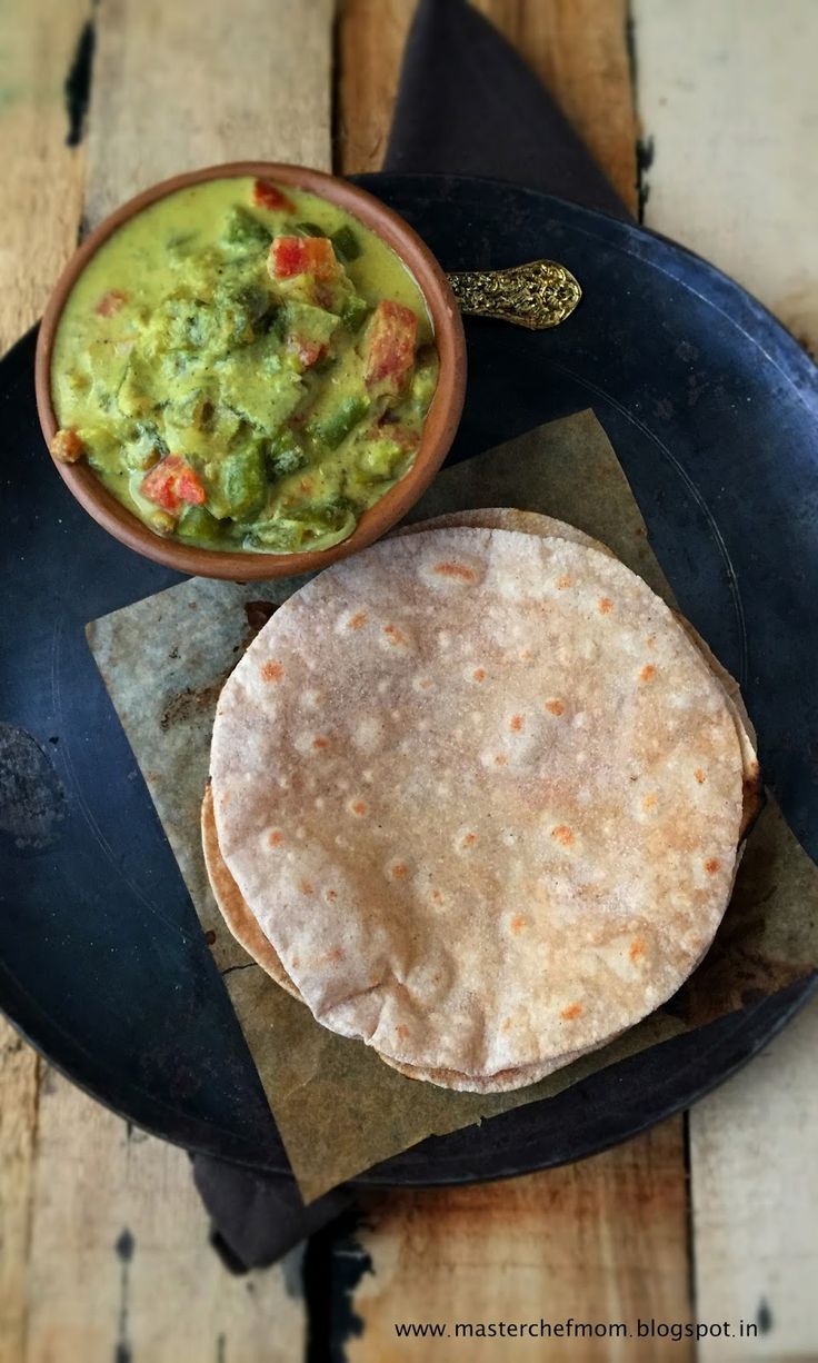 a tortilla and guacamole on a black plate with a spoon