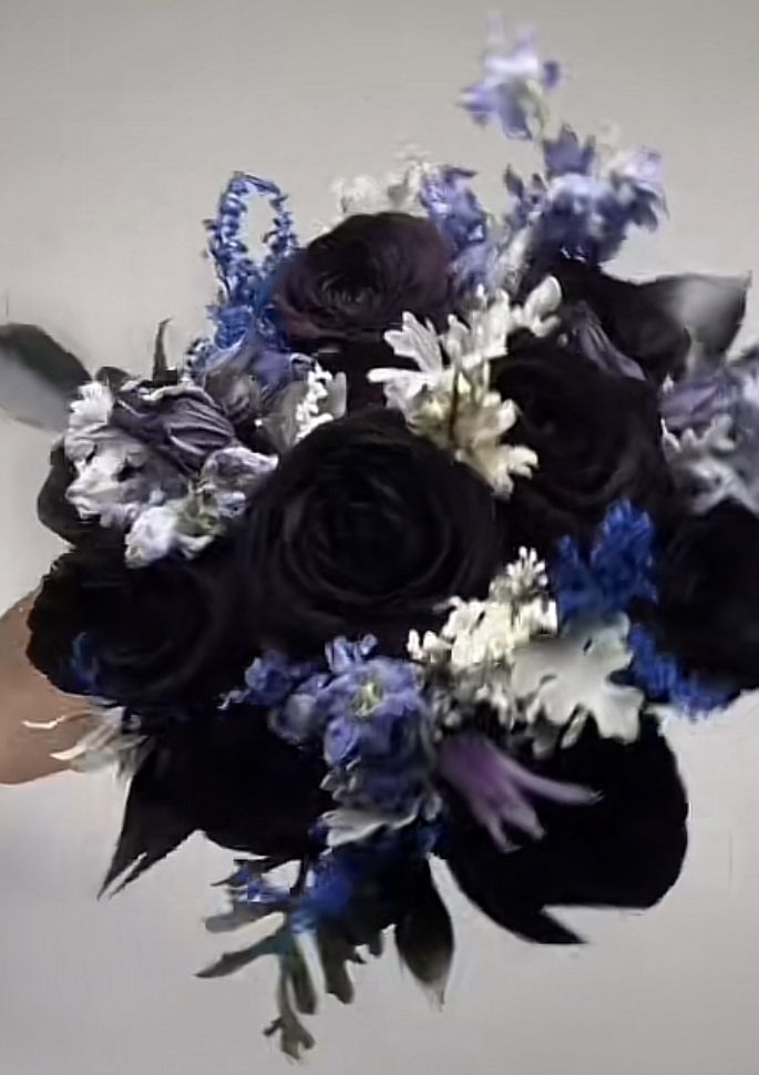 a bridal bouquet with blue and white flowers in it is being held by someone's hand