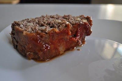 a piece of meatloaf sitting on top of a white plate covered in sauce