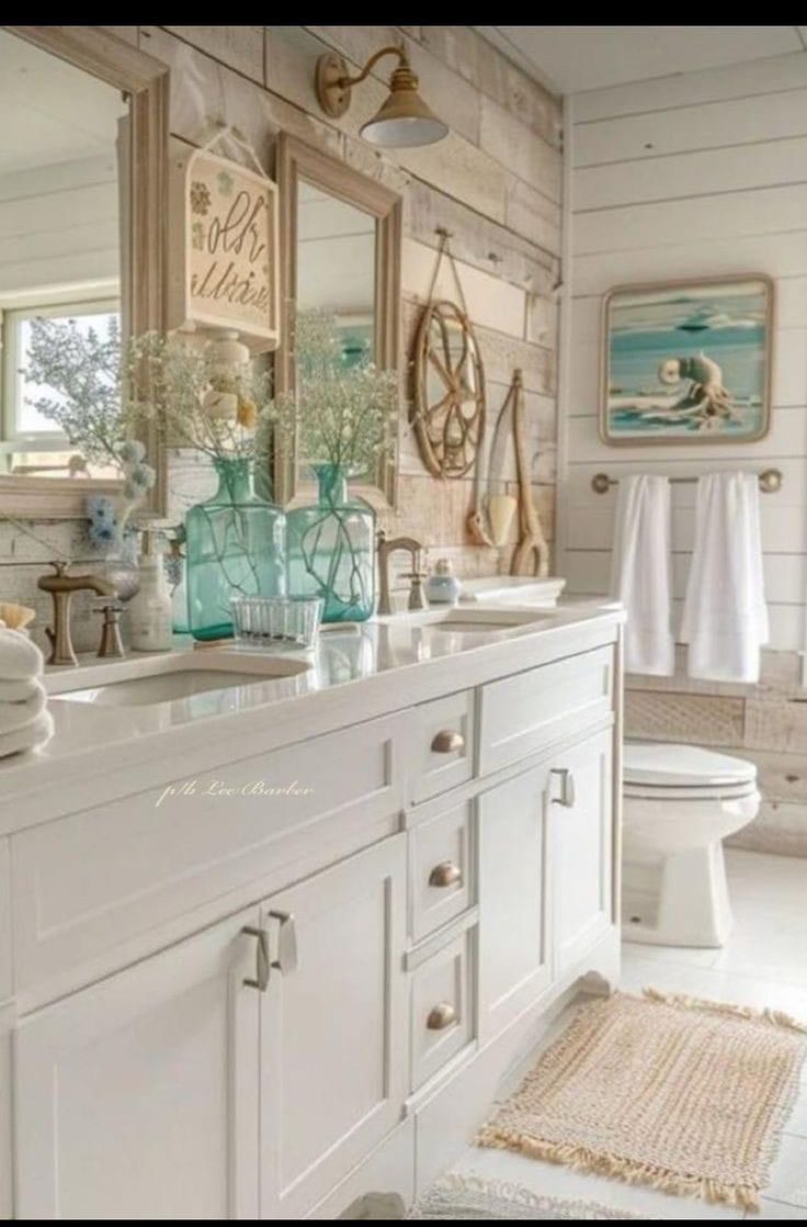 a bathroom with white cabinets and blue vases on the counter top, along with two mirrors