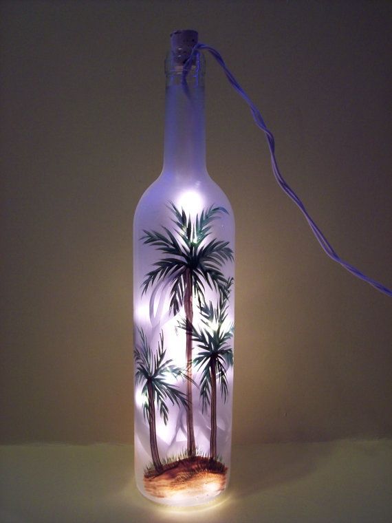 a bottle with palm trees in it is lit up by a string and some lights