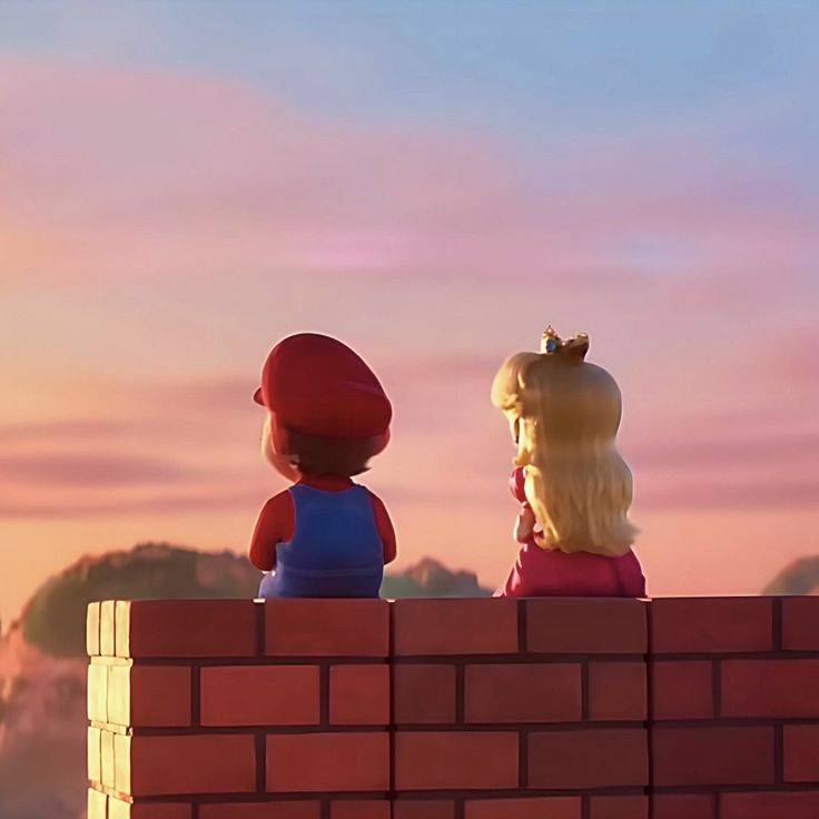 two legos sitting on top of a brick wall looking at the sky and mountains