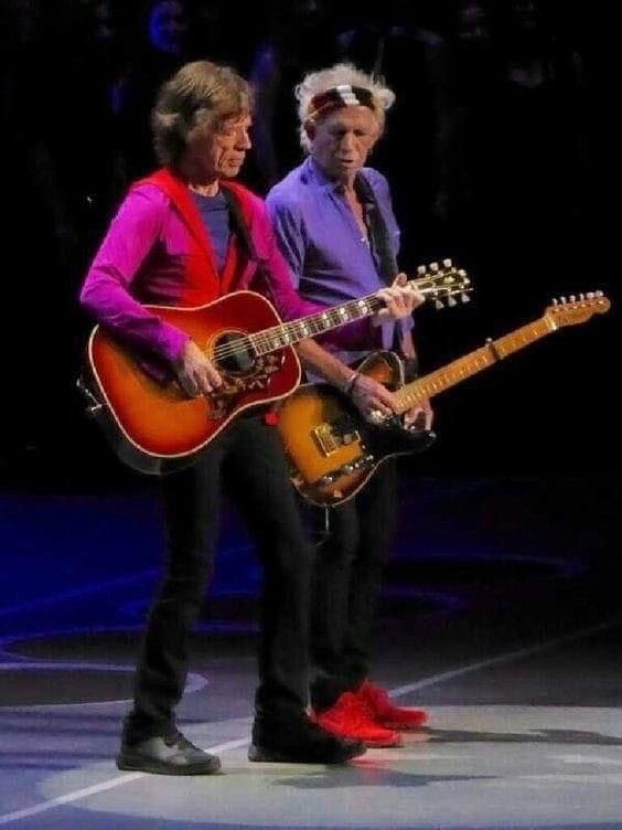 two men are playing guitars on stage