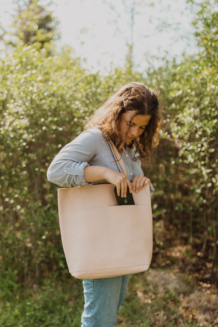 A classic leather tote is a wardrobe staple every girl needs in their life. And these beauties are here in our fun new colours to add a pop of color to your wardrobe! Its buttery soft leather and minimalistic yet functional design makes this a bag that will fit seamlessly into your life. Whether it’s tagging along for a weekend trip to the farmer’s market, holding all your work or school necessities, or traveling with you around the world, you’ll find this beautiful genuine leather tote the bag Feminine Leather Tote Bag, Modern Tan Tote Bag, Cream Soft Leather Tote Bag, Beige Tote Bag With Leather Lining, Blush Leather Tote Bag, Bag Poses, School Necessities, Classic Leather Tote, Genuine Leather Totes