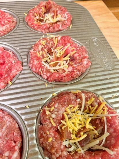 some meat and cheese are in the muffin tins ready to go into the oven