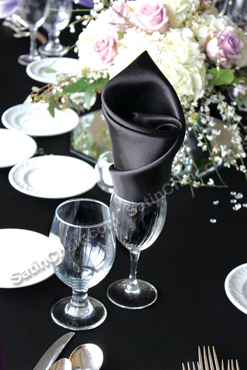 the table is set with silverware and black napkins, white flowers, and an elegant centerpiece