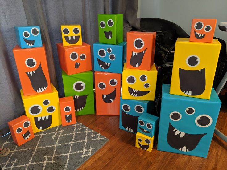 colorful blocks with faces painted on them sitting in front of a chair and window curtain