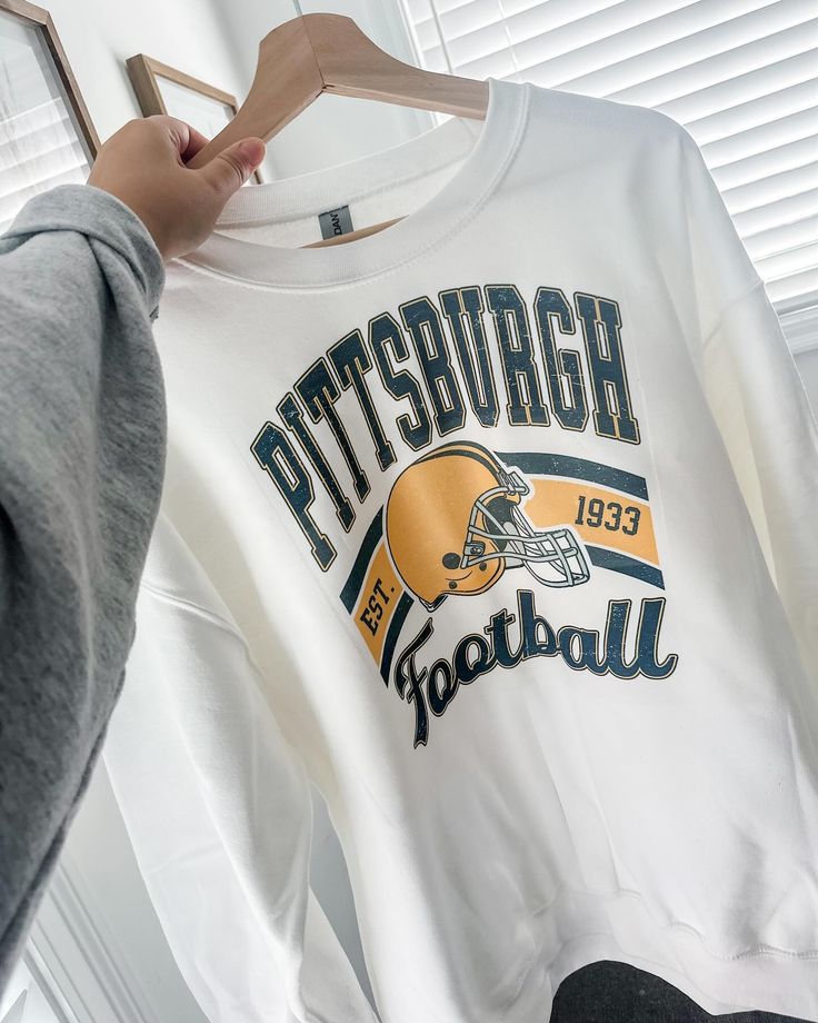 a football sweatshirt hanging on a hanger next to a person's hand holding it up