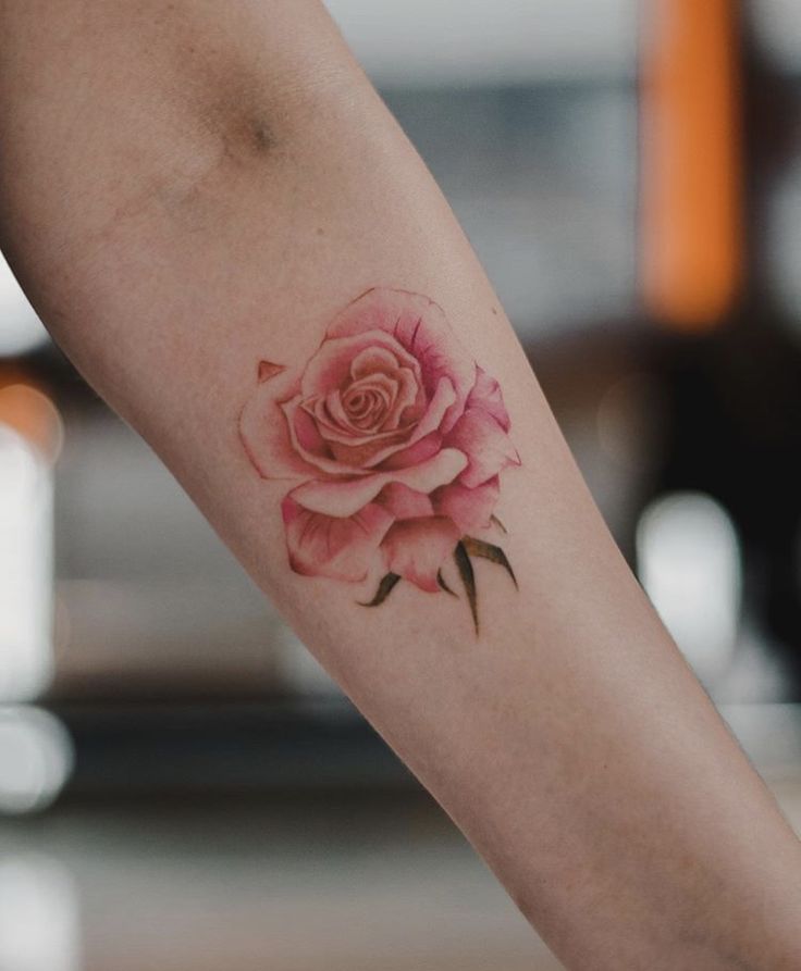 a woman's arm with a pink rose tattoo on it