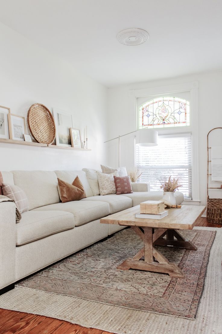 a living room with white couches and wooden coffee table in front of a window