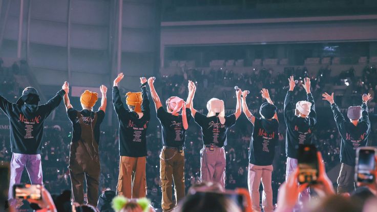 a group of people standing on top of a stage with their hands in the air