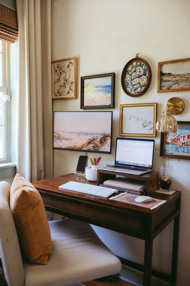 a laptop computer sitting on top of a wooden desk next to a chair and window