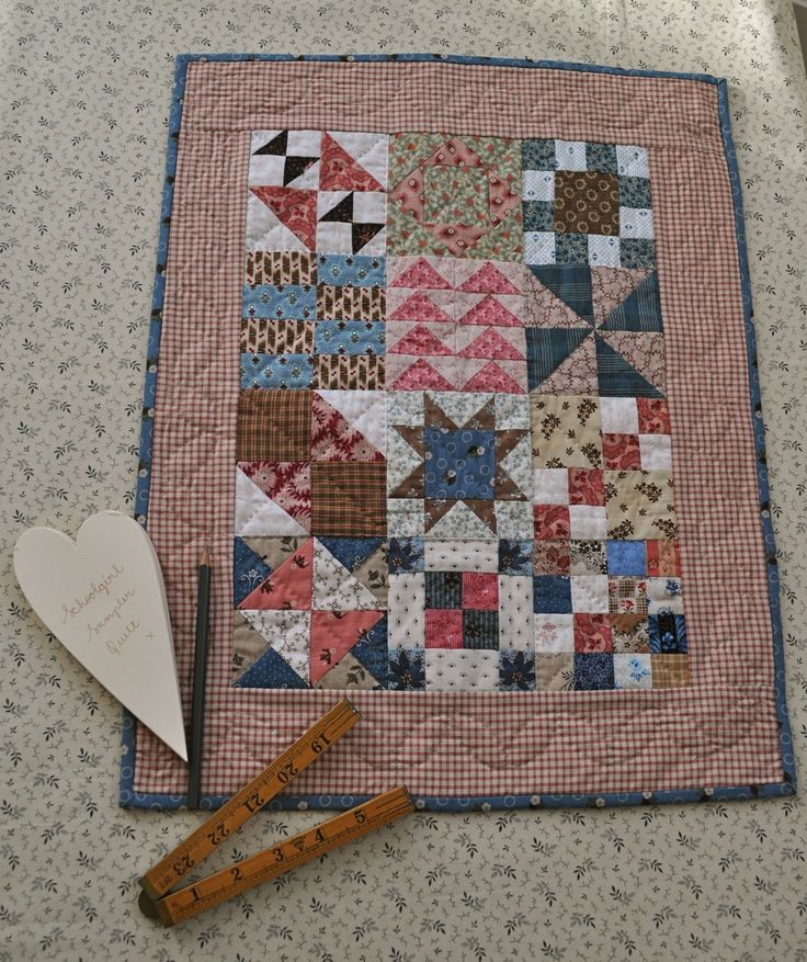 a piece of quilt next to a ruler on a table with a heart and pen