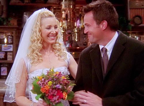 a man and woman standing next to each other in front of a bar with flowers