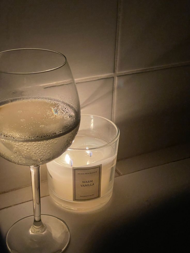 a glass of wine next to a lit candle