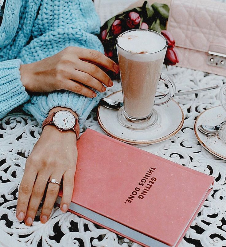 a woman sitting at a table with a book and cup of coffee next to her