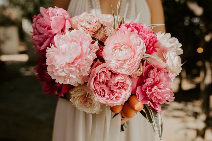 a woman holding a bouquet of pink and white flowers