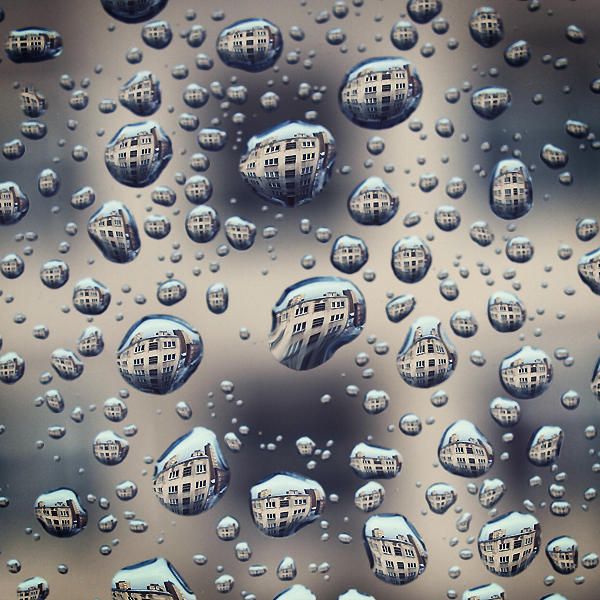 water droplets on a window pane with buildings in the background