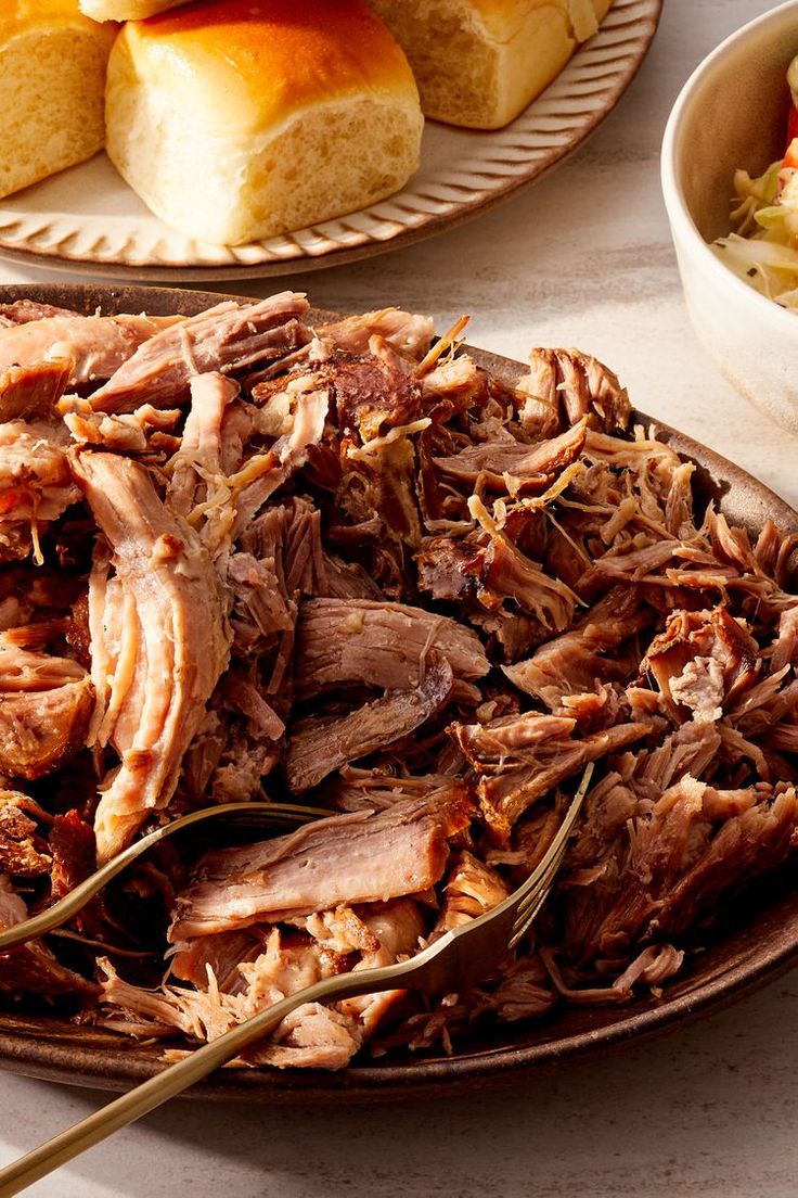 pulled pork on a plate with rolls in the background