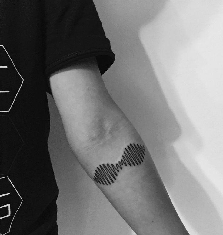 a black and white photo of a person's arm with a sound wave tattoo on it