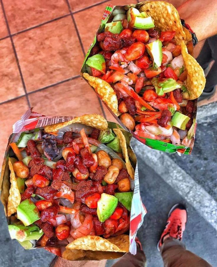 two tacos filled with meat and vegetables on top of each other next to red shoes