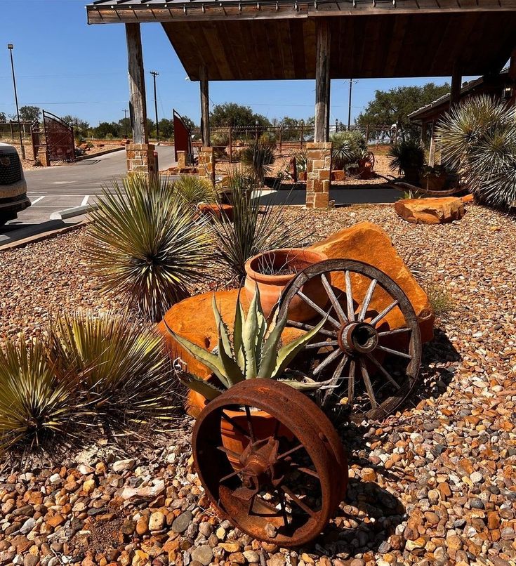 an old wagon with wheels is sitting in the gravel near some plants and other things