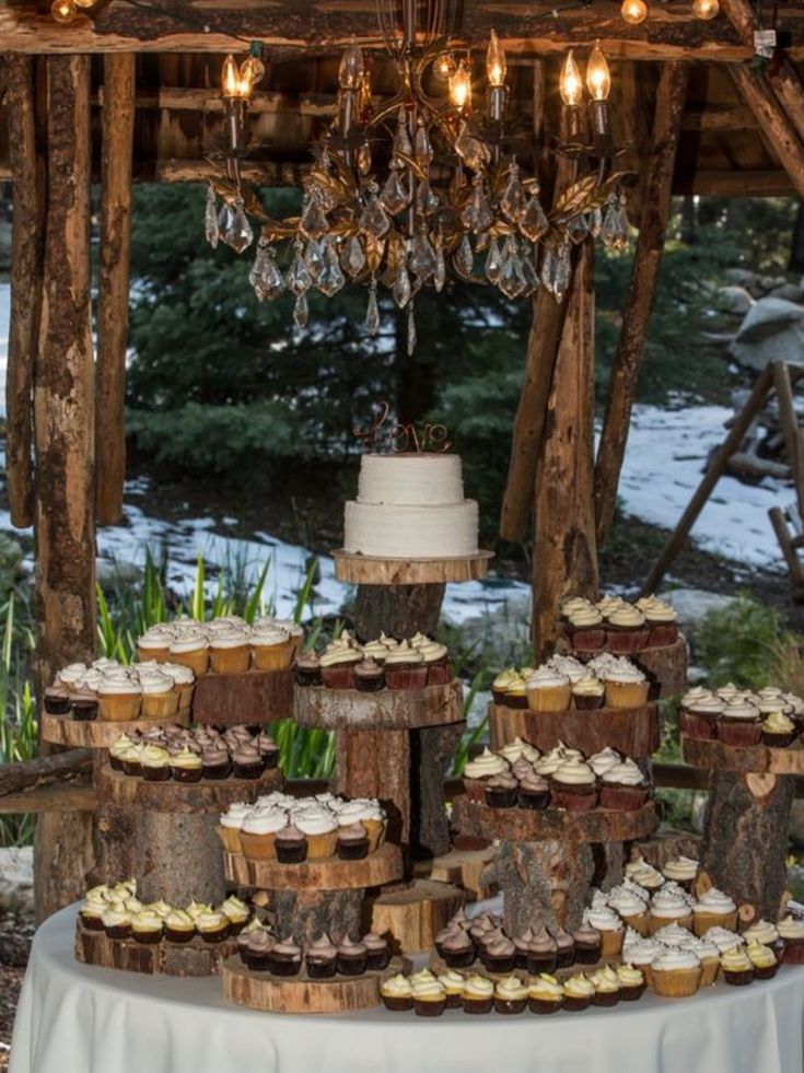 a table topped with lots of cupcakes under a chandelier