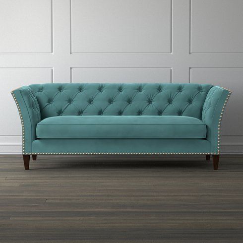 a blue couch sitting on top of a hard wood floor next to a white wall