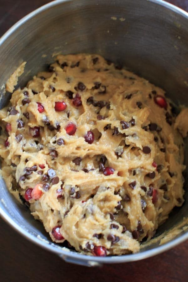 a metal bowl filled with batter and cranberry toppings on top of a wooden table