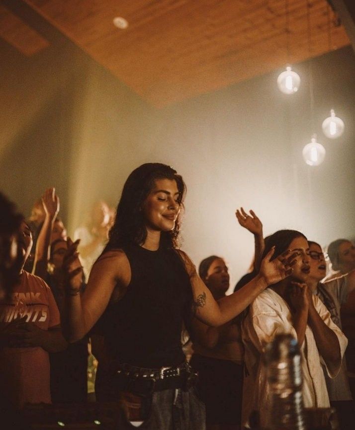 a group of people standing around each other at a music concert with their hands in the air