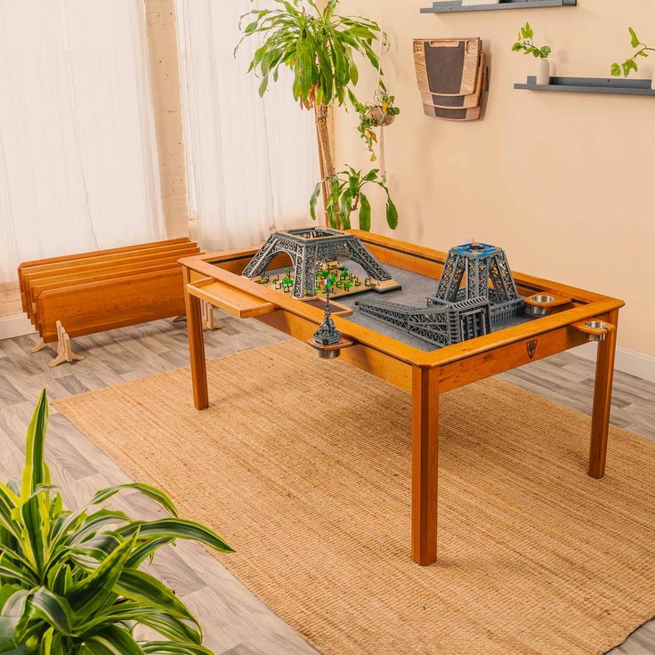 a table that has some cars on it in the middle of a room with plants