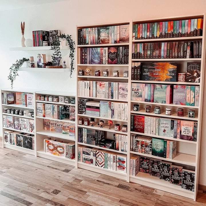 a book shelf filled with lots of books on top of wooden flooring next to a white wall