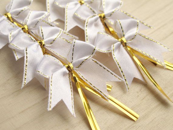 four white bows with gold pins on them