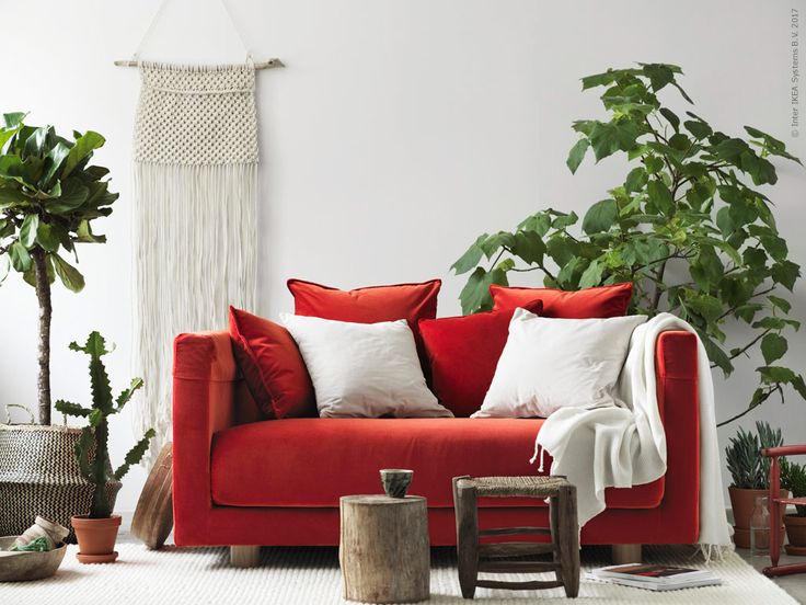 a living room with red couches and potted plants on the floor in front of white walls