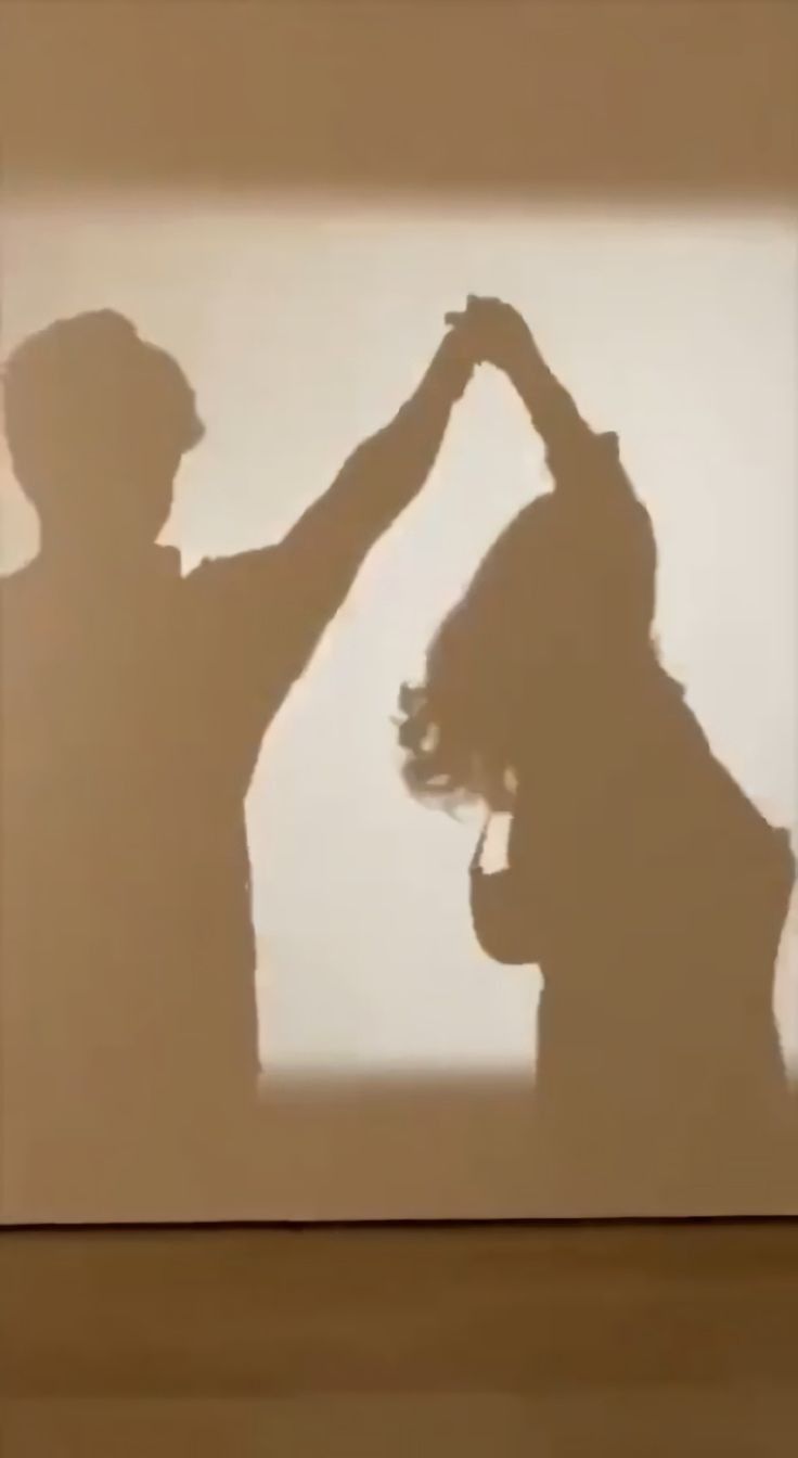 the shadow of two people making a heart shape with their hands