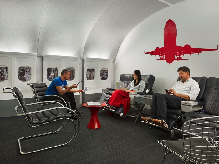 two people sitting in chairs on an airplane with a red plane painted on the wall