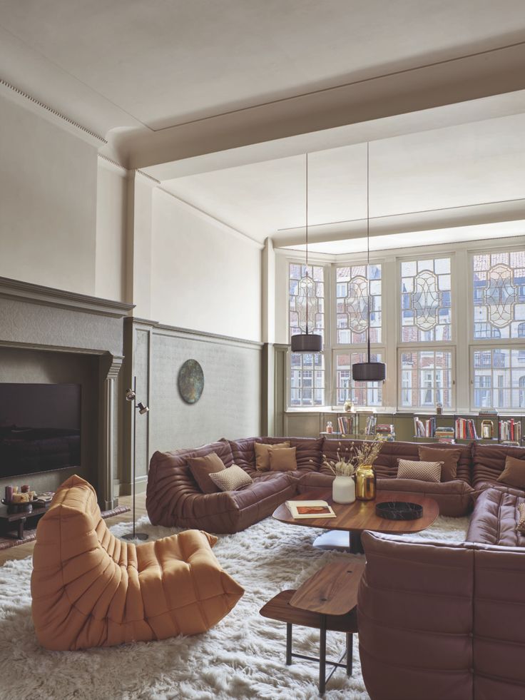 a living room filled with lots of furniture and a fire place in front of a large window