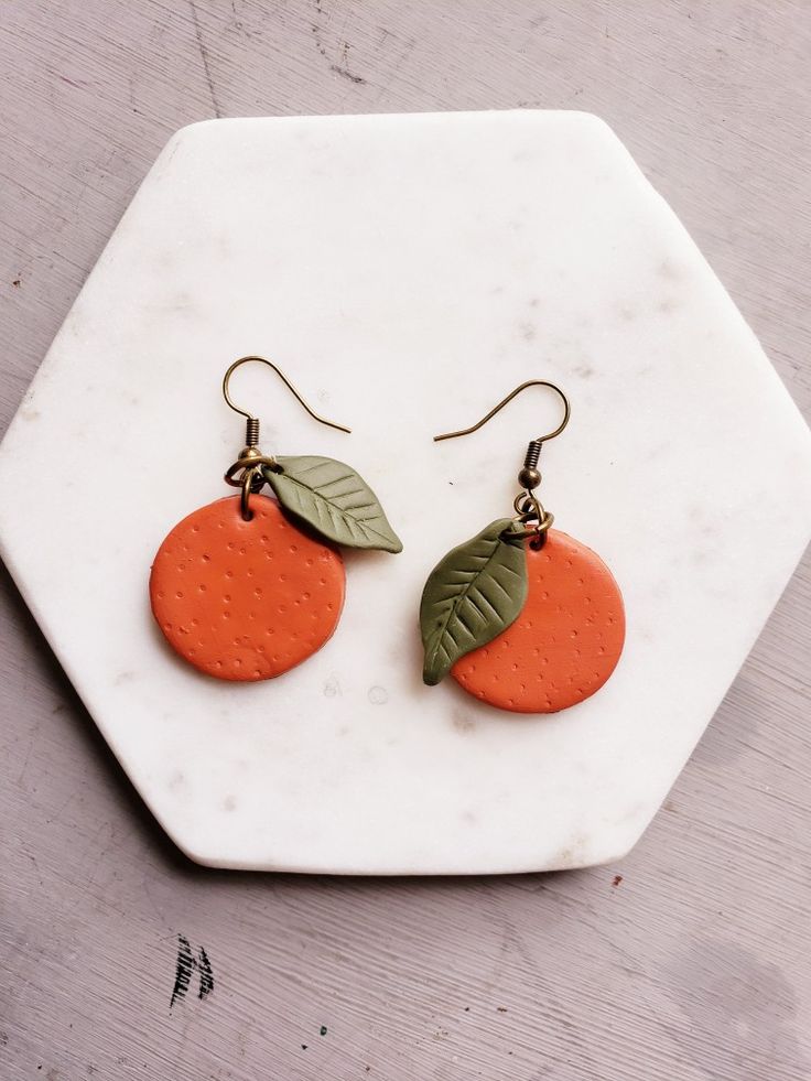 two oranges with leaves on them sitting on a white plate