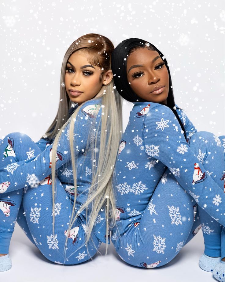 two women in blue pajamas sitting on the ground with snowflakes all over them