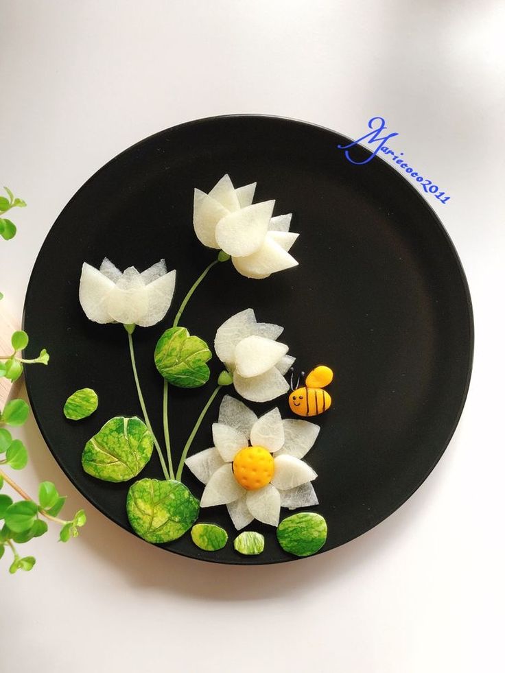 a black plate topped with white flowers and a bee sitting on top of each other