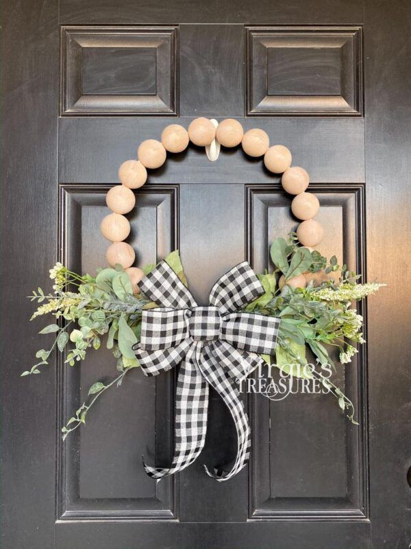 a black and white wreath with greenery on the front door