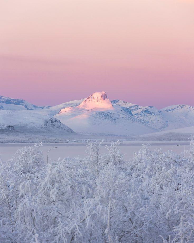 the mountains are covered in snow as the sun is setting behind them and there is no image to provide a caption for