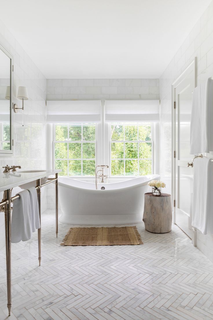 a bathroom with a large white bathtub next to a window