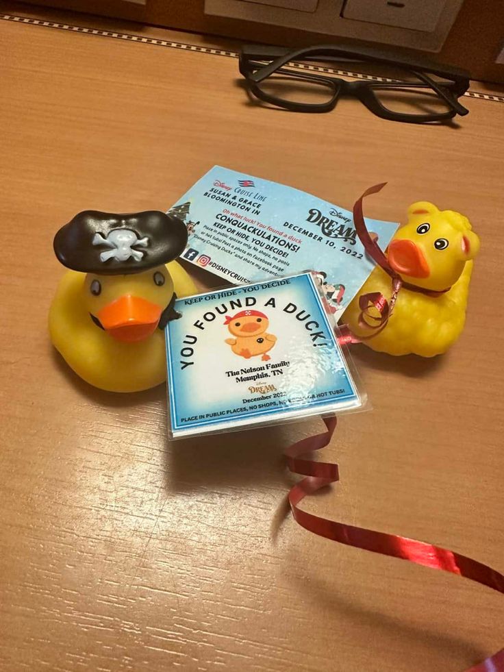 two rubber ducks with pirate hats on their heads are sitting next to a book and ribbon