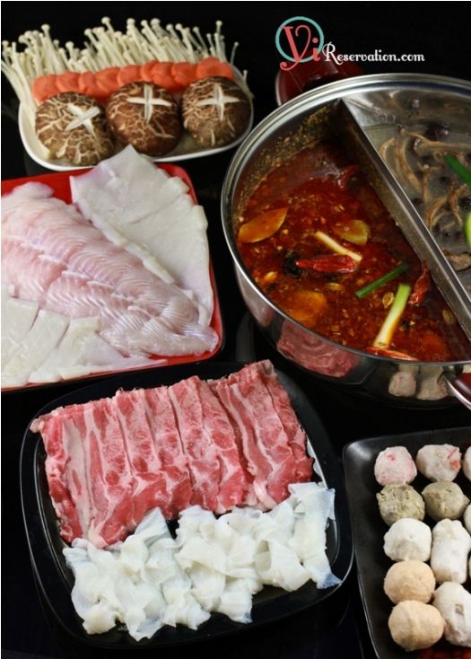 an assortment of meats and vegetables are displayed in trays on a black surface