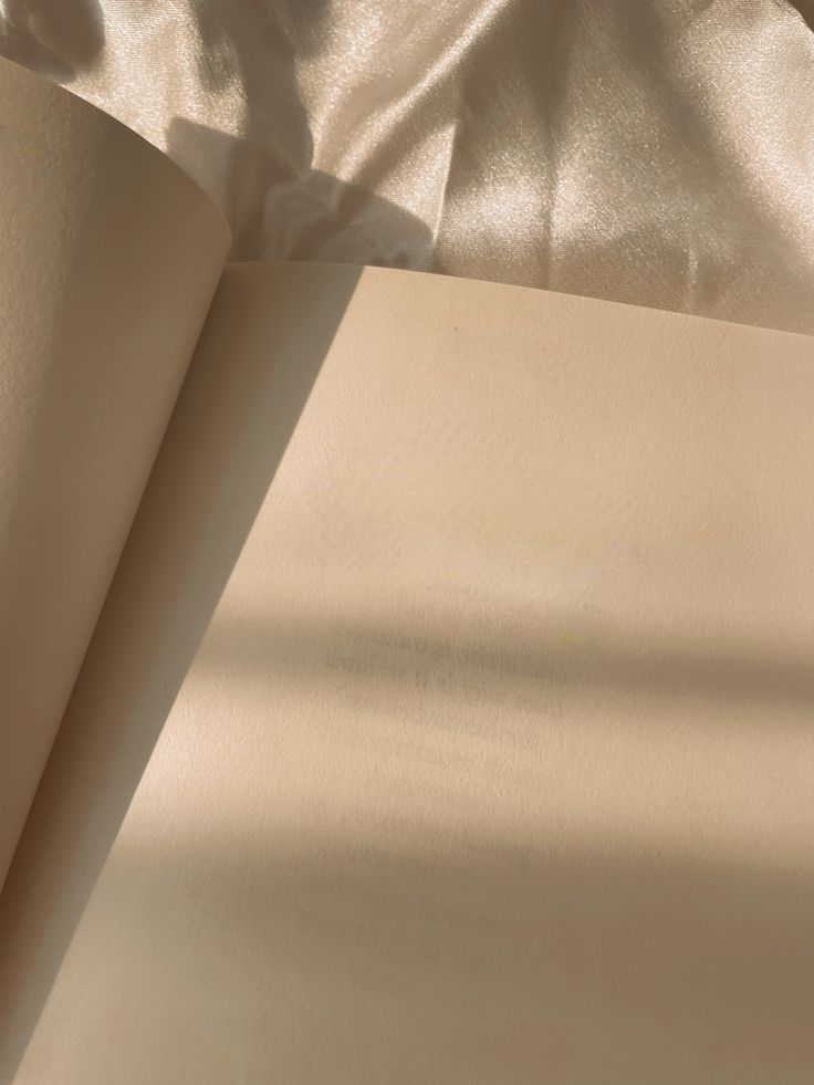 an open book sitting on top of a bed next to a white sheet and pillow