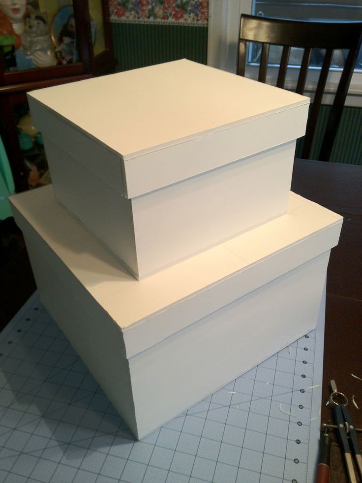 three white boxes sitting on top of a table next to a pair of pencils