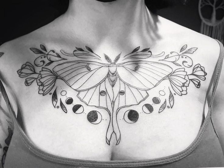 a black and white photo of a woman's chest with a butterfly tattoo on it